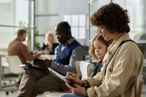 Mother and daughter filling application forms while waiting in line